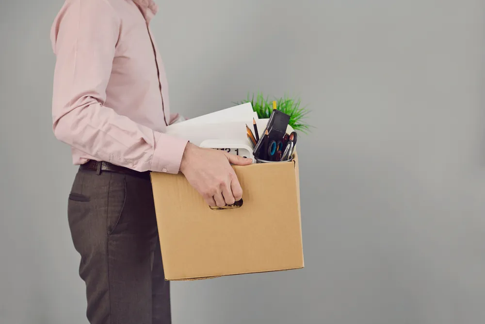 Person holding a box of personal belongings after losing their job.