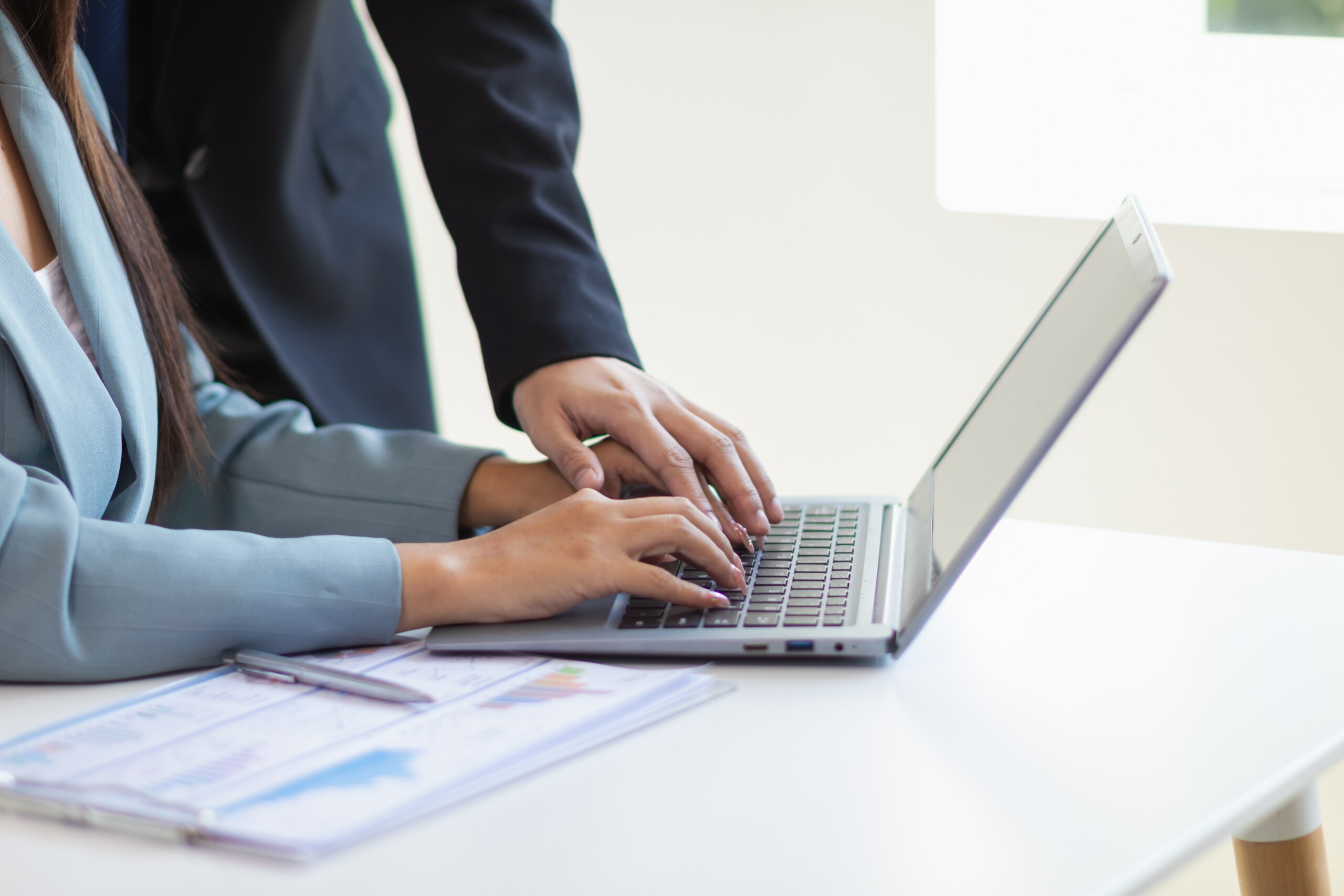 Employees reviewing documents on a laptop, illustrating how the federal Silence No More Act impacts workplace NDAs in Florida.